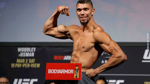 UFC拳手在稱重活動中與BodyArmor標誌一起彎曲肱二頭肌。 — 艾倫·沃克 GIF 壁紙