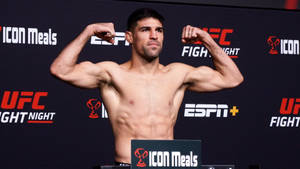 UFC拳手在稱重活動中彎曲手臂，背景有ESPN和ICON Meals標誌。 — 終極格鬥冠軍賽 壁紙