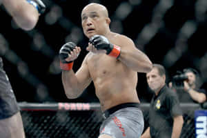 一位穿著灰色短褲的男性MMA戰士在比賽中於八角籠內揮拳。 — 運動 壁紙