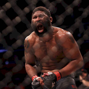 一位肌肉發達的MMA戰士在UFC八角籠中，模糊籠網背景下咆哮。 — 終極格鬥冠軍賽 壁紙