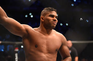 一位勝利的MMA戰士在競技場燈光下於八角籠中舉起手臂。 — 運動 壁紙