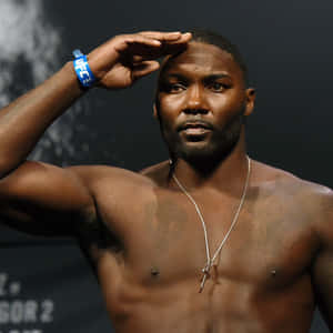 一位赤裸上身的戰士戴著UFC腕帶和十字架項鍊，以專注的表情敬禮。 — 終極格鬥冠軍賽 壁紙