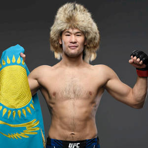 一位赤裸上身的哈薩克戰士戴著毛帽，手持國旗並與UFC腰帶一起擺姿勢。 — 運動 壁紙