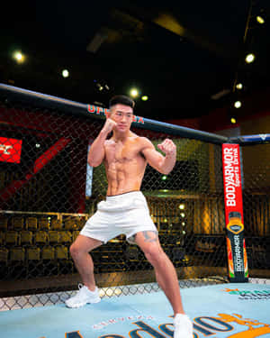 運動型拳手穿著白色短褲在UFC八角籠內擺姿勢。 — 運動風 壁紙