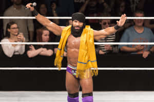 擂台上的摔角手拿著麥克風和黃色圍巾向歡呼的粉絲揮手。 — WWE GIF 壁紙