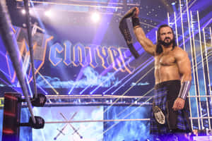 穿著蘇格蘭裙的摔角手在場中高舉冠軍腰帶。 — WWE GIF 壁紙