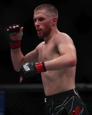 一位赤裸上身的男性MMA拳手，在八角籠內戴著黑色和紅色手套。 — 終極格鬥冠軍賽 壁紙