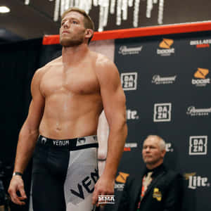 肌肉發達的MMA拳手穿著Venum短褲，在稱重活動中，身後有贊助商標誌。 — 運動 壁紙