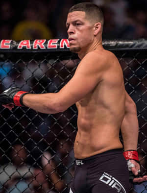 一位赤裸上身的MMA拳手穿著黑色短褲和紅色手套站在八角籠內。 — 終極格鬥冠軍賽 壁紙