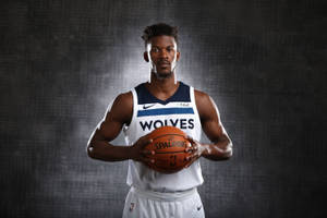 職業籃球運動員身穿狼隊球衣，在深色背景前拿著一個 Spalding 籃球。 — 黑狼 壁紙