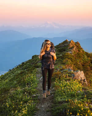 遠足者在山徑上欣賞夕陽，背景有白雪覆蓋的山峰 — Apple Watch Ultra 壁紙