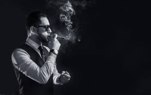男士戴著太陽眼鏡在黑暗的攝影棚中抽雪茄，煙霧繚繞。 — 抽菸 壁紙