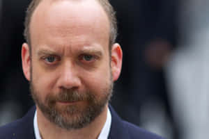 穿著深色西裝、灰色鬍鬚的男士直視相機。 — 斯特凡·薩爾瓦托雷 壁紙