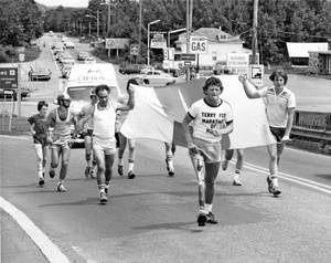 馬拉松選手，包括一位裝有義肢的，沿著道路跑過汽車和加油站。 — 福斯新聞 壁紙