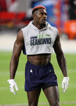 西雅圖海鷹隊美式足球員在球場上，身穿短版連帽衫和手套 — Dk Metcalf 壁紙