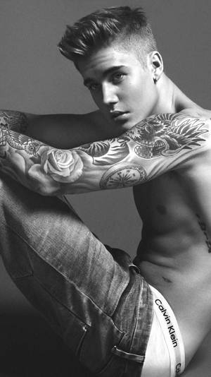 有刺青的年輕男子穿著牛仔褲和Calvin Klein內褲擺姿勢。 — 小賈斯汀 壁紙