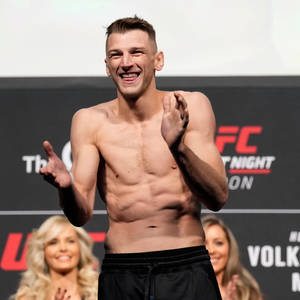 UFC拳手在過磅活動中微笑鼓掌，身後有粉絲。 — 運動 壁紙