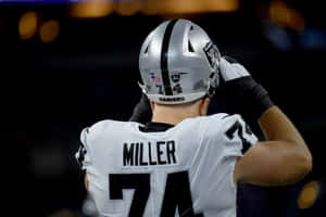 Raiders 74號美式足球員在夜間比賽中調整頭盔。 — 運動 壁紙