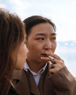 兩位女性在戶外，其中一位將香煙靠近嘴唇 — 抽菸 壁紙