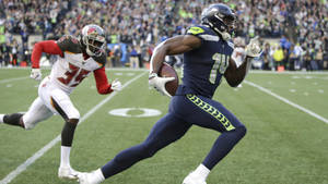 西雅圖海鷹隊球員帶球奔跑，坦帕灣海盜隊防守球員追趕。 — Dk Metcalf 壁紙