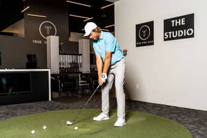 高爾夫球手在True Spec Golf Studio室內揮桿 — 標誌 壁紙