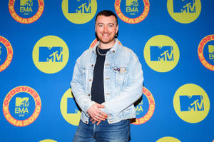 身穿牛仔外套的男子在MTV EMA 2020活動背景前微笑。 — 山姆·史密斯 壁紙