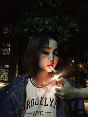 年輕女性在戶外夜晚穿著牛仔外套點燃香煙。 — 抽菸 壁紙