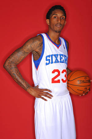 身穿Sixers球衣的職業籃球運動員，在紅色背景前手持Spalding籃球。 — 費城76人 壁紙