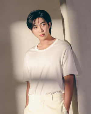 身穿白衣的年輕男子靠在陽光照射的牆上 — BTS RM 壁紙
