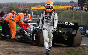 F1車手從受損的AlphaTauri賽車旁走開，維修人員正在處理。 — 白色 壁紙