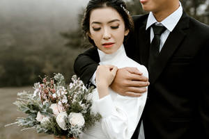 新娘和新郎在霧氣瀰漫的森林中擁抱，手持花束。 — 婚紗 壁紙