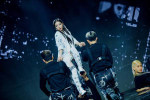 K-pop 舞者在黑暗舞台上，在發光背景前表演編排好的托舉動作。 — 청하 壁紙