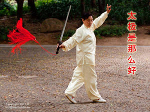 一位長者在公園中用劍和紅色流蘇練習太極拳。 — 運動 壁紙