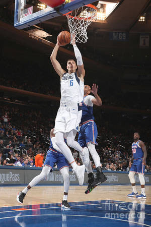 NBA比賽中，身穿白色球衣的籃球球員在藍色球衣防守球員上方灌籃。 — 波士頓塞爾提克 壁紙