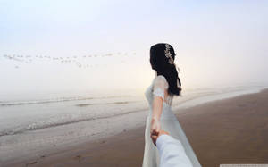 新娘和新郎在日出時分，手牽手走在霧濛濛的海灘上。 — 婚紗 壁紙