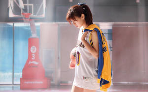 身穿籃球服的年輕女子在體育館內拿著球 — 運動 壁紙
