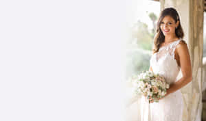 身穿白色蕾絲裙的新娘手持花束，在戶外陽光下微笑。 — 婚紗 壁紙
