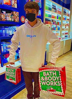 年輕男子戴著口罩，在商店裡拿著Bath & Body Works節日購物袋。 — 卡爾·雅各布斯 壁紙