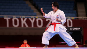 身穿白色道服、繫紅色腰帶的女空手道選手在東京2020場館比賽。 — 運動風 壁紙