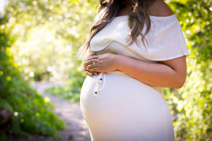 孕婦在陽光明媚的花園中抱著肚子。 — 懷孕 壁紙