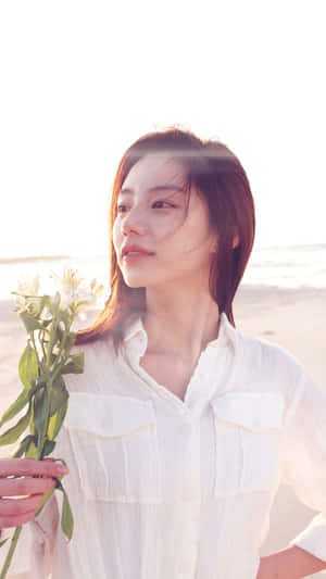 女性在陽光海灘上手持白色花朵 — 海灘日落 壁紙