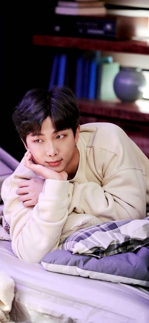 身穿米色連帽衫的年輕男子在鋪著紫色格子毯子的床上休息。 — BTS 紫色美學 壁紙