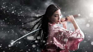 一位身穿粉紅色和服的武士女子，在雪花飄落中手持一把劍。 — 日本武士 壁紙