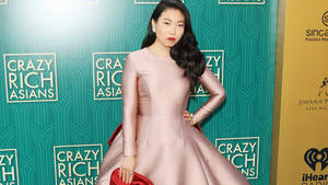 身穿粉紅色緞面連衣裙的女性在 Crazy Rich Asians 活動中擺姿勢。 — 瘋狂的亞洲富豪 壁紙