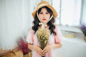 年輕女性身穿粉紅色連衣裙和草帽，在室內手持乾花。 — 可愛粉色女孩 壁紙
