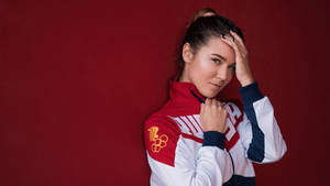 身穿團隊外套的女奧運運動員在紅色背景下將手放在頭上擺姿勢。 — 奧運 壁紙