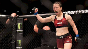 女性MMA拳手在UFC八角籠中高舉拳頭慶祝勝利。 — 運動 壁紙