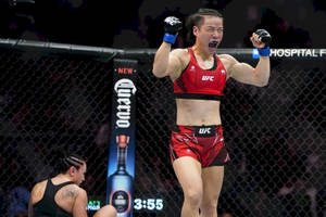 女性MMA拳手在UFC八角籠中慶祝勝利，對手倒地。 — 運動 壁紙