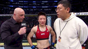 UFC拳手在八角籠內接受採訪，旁邊有一位身穿白色連帽衫的男子。 — 運動 壁紙