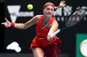 身穿紅色運動服的女子網球選手在比賽中用球拍擊打綠色球。 — 運動 壁紙